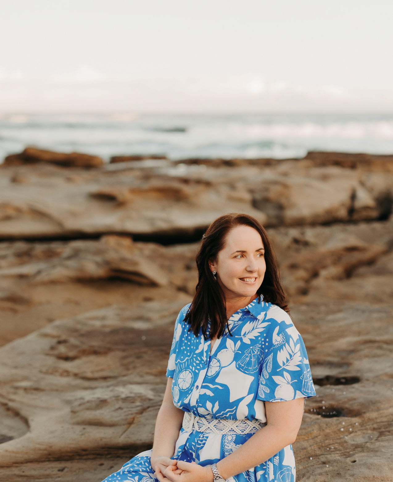 SEO content writer Jane Havercroft sits on the rocks at the beach